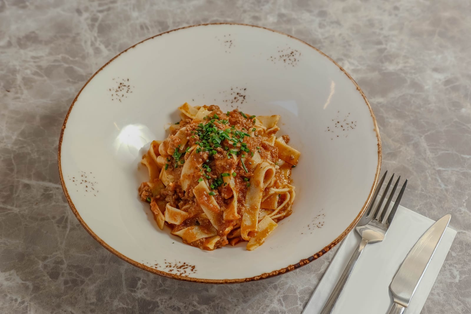 Tagliatelle al ragù in un piatto bianco rustico