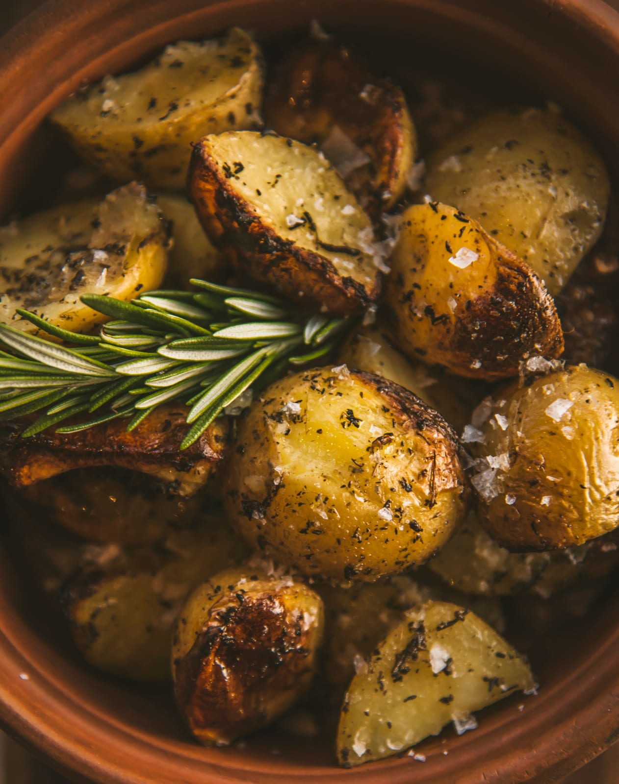 Spicchi di patate arrosto alle erbe in una ciotola di terracotta