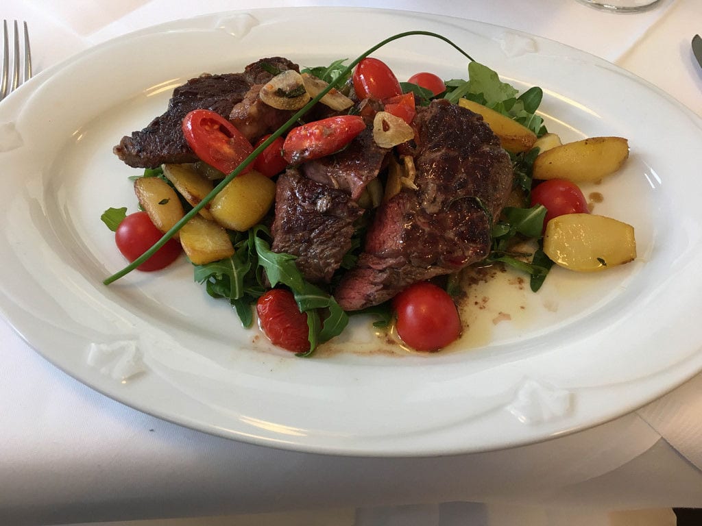 Carne alla griglia tagliata a fette su rucola, foto illustrativa