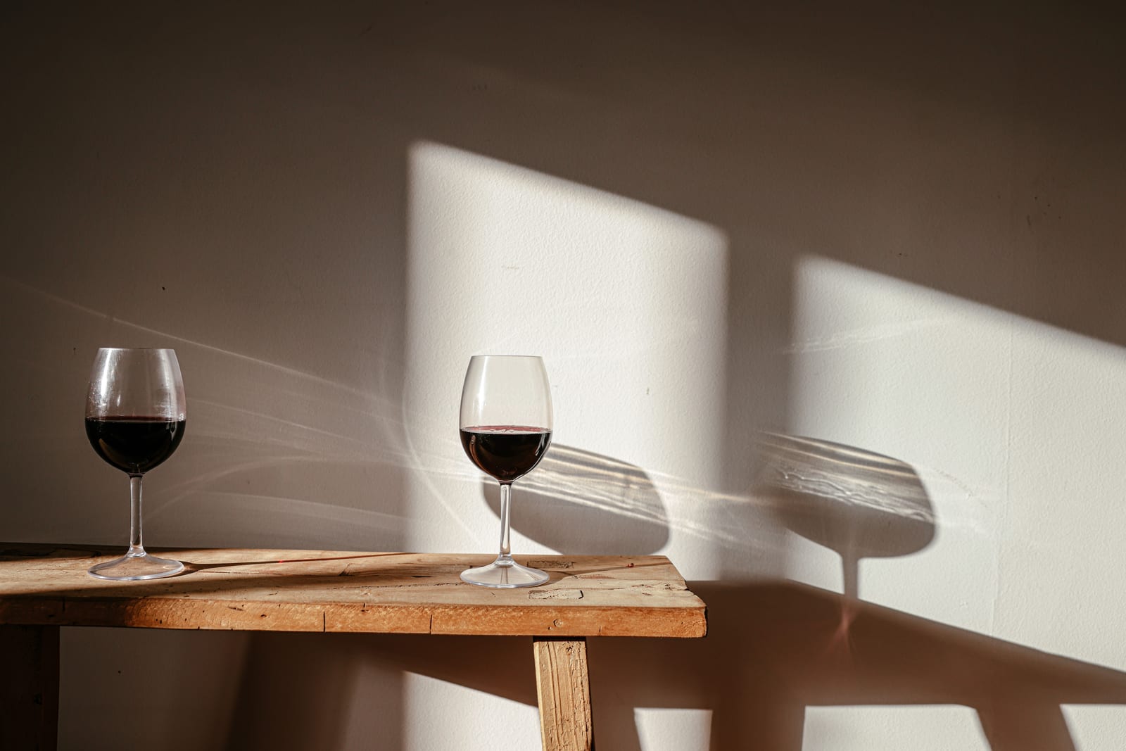 Due calici di vino rosso su legno alla luce del sole, foto illustrativa